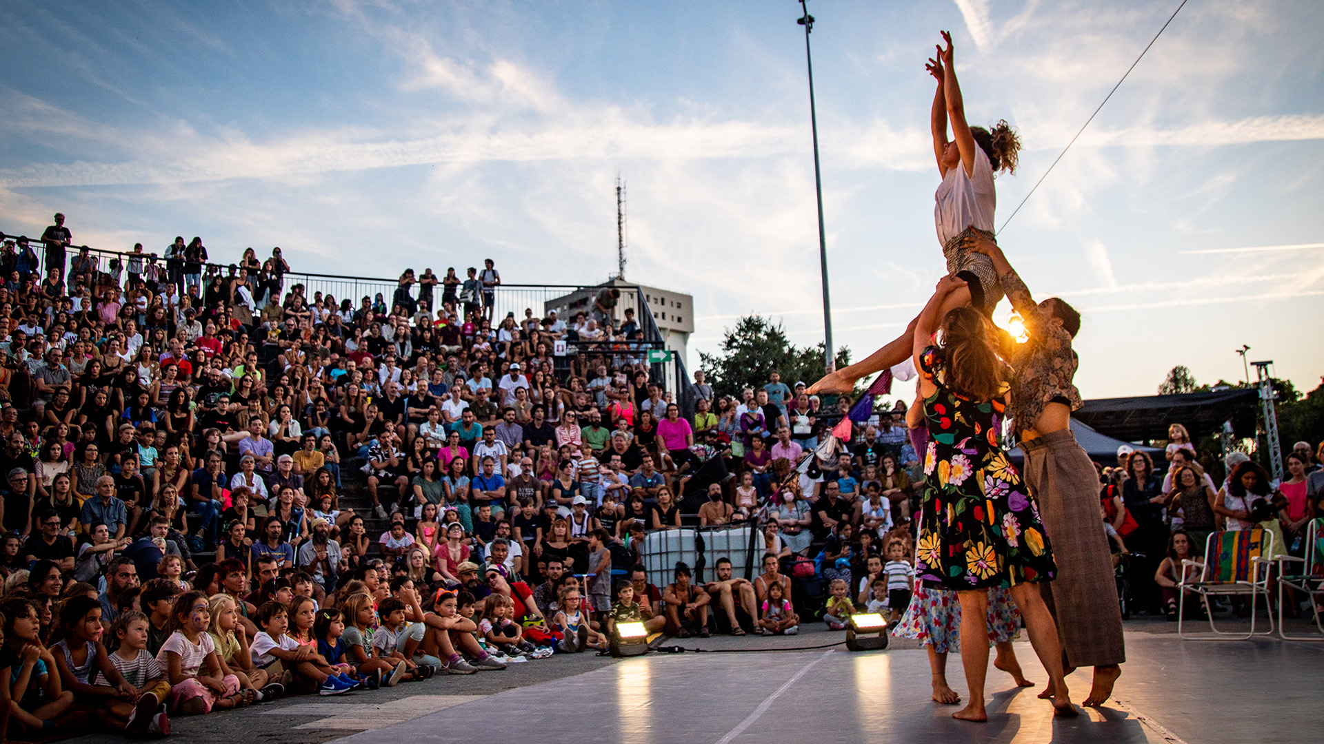 Quattro danzatori si esibiscono di fronte a un pubblico pieno di persone e bambini